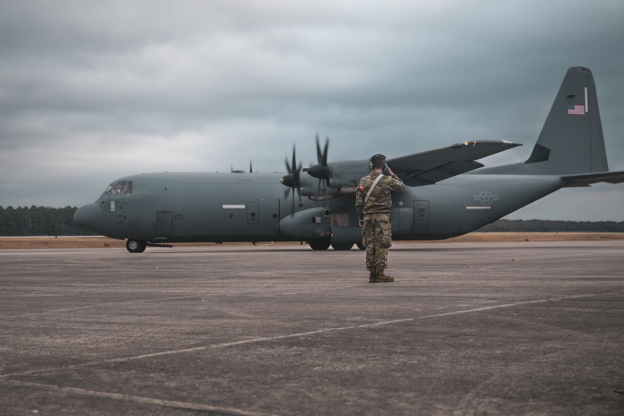 An airman salutes as an aircraft departs the base.
