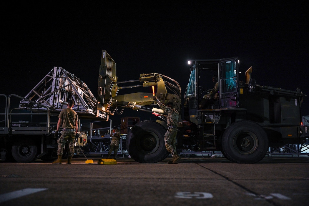 Airmen load cargo during an exercise at night.