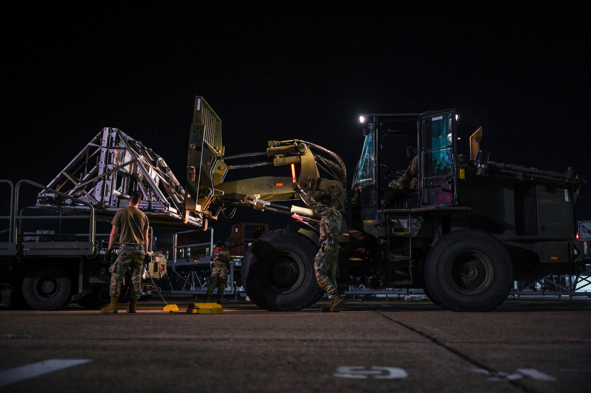 Airmen load cargo during an exercise at night.