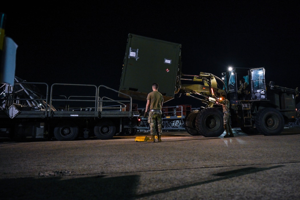 Airmen load cargo during an exercise at night.