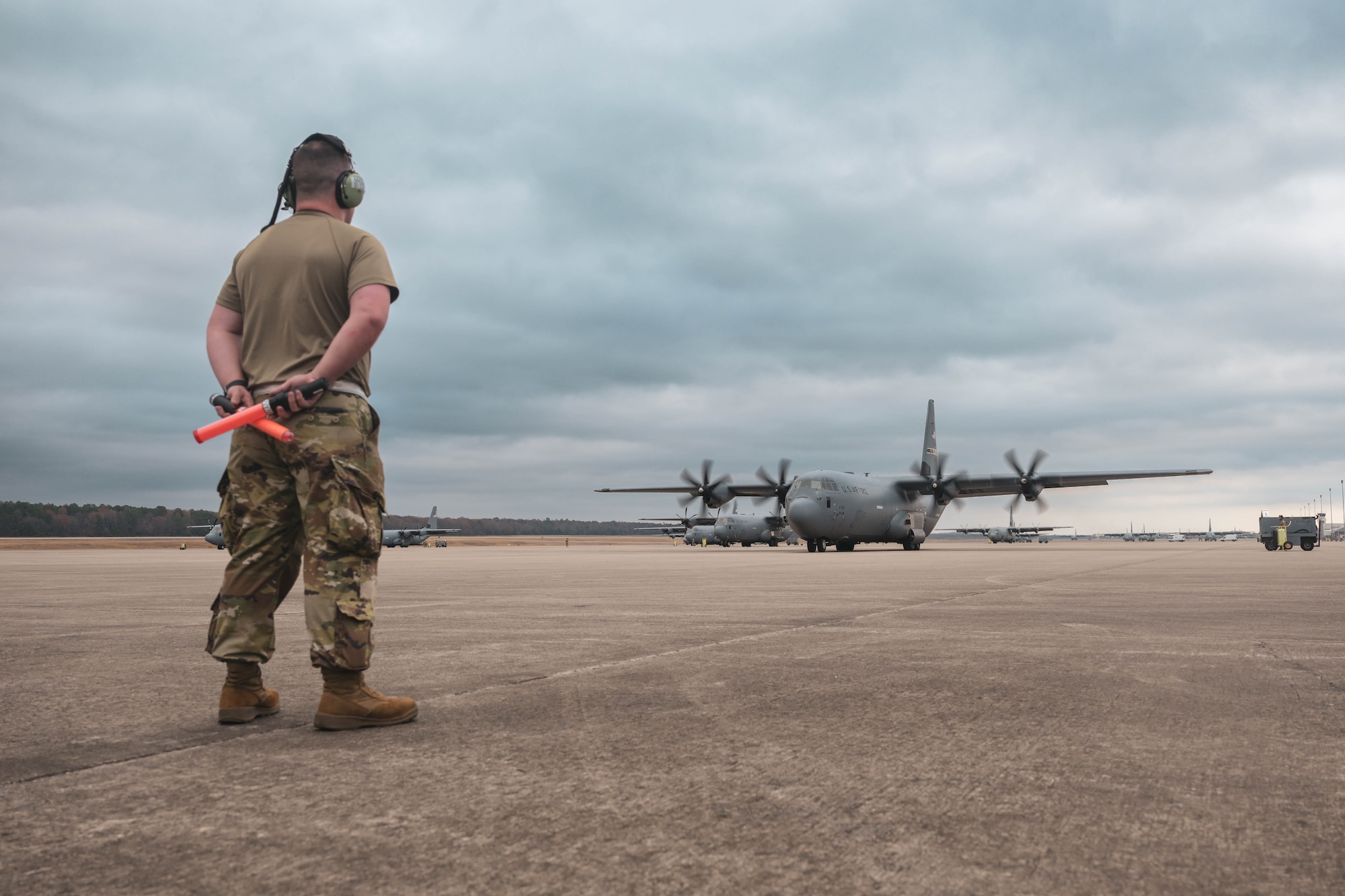 A crew chief stands at parade rest as an aircraft prepares to depart the base.