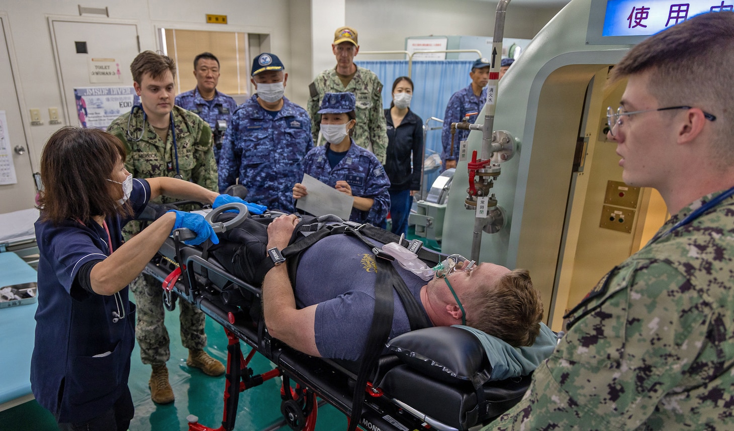 TAURA, Japan (Nov. 18, 2025) — Medical personnel from U.S. Naval Hospital Yokosuka and the Japan Maritime Self-Defense Force Undersea Medical Center conduct a rapid evaluation of a simulated diving casualty during a bilateral emergency medical drill. The exercise rehearsed coordinated response, transport, and evaluation procedures for a simulated diving-related embolism. (U.S. Navy photo by Daniel Taylor/USNMRTC Yokosuka Public Affairs)
