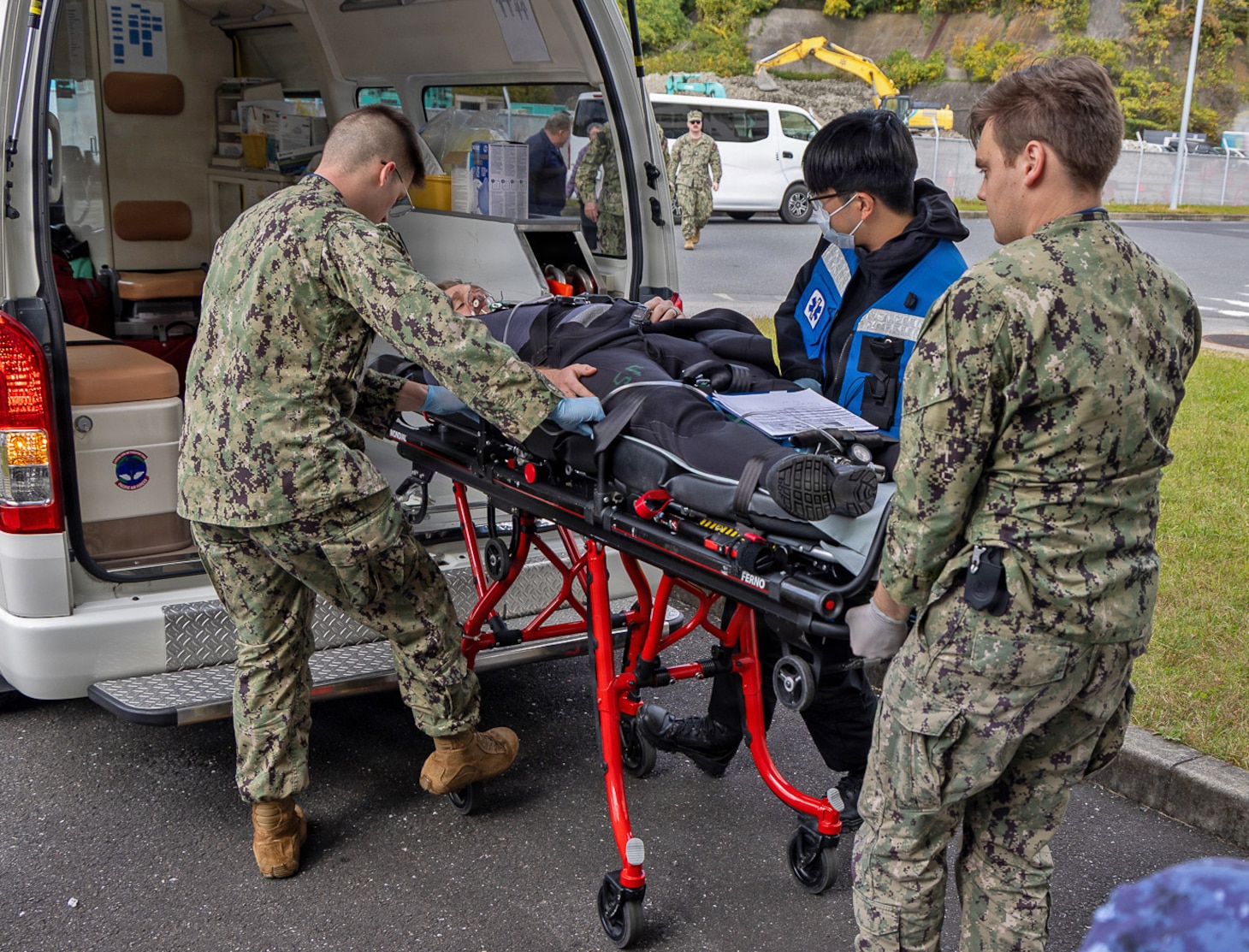 TAURA, Japan (Nov. 18, 2025) — U.S. Navy hospital corpsmen and a master labor contractor driver from U.S. Naval Hospital Yokosuka transport a simulated diving casualty to the Japan Maritime Self-Defense Force Undersea Medical Center hyperbaric chamber during a bilateral emergency medical drill. The exercise rehearsed coordinated response, transport, and evaluation procedures for a simulated diving-related embolism. (U.S. Navy photo by Daniel Taylor/USNMRTC Yokosuka Public Affairs)