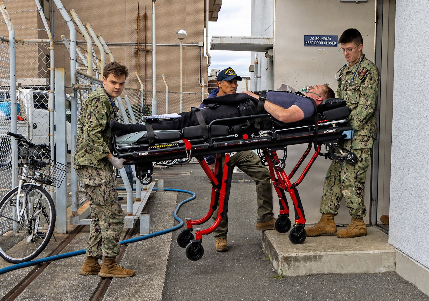 YOKOSUKA, Japan (Nov. 18, 2025) — U.S. Navy hospital corpsmen assigned to U.S. Naval Hospital Yokosuka transport a simulated casualty from a dive locker during a bilateral emergency medical drill involving Commander, Submarine Group Seven; U.S. Naval Hospital Yokosuka; Japan Self-Defense Force Hospital Yokosuka; Japan Maritime Self-Defense Force Undersea Medical Center; and the Navy Dive Locker at U.S. Naval Ship Repair Facility and Japan Regional Maintenance Center. The exercise rehearsed coordinated response, transport, and evaluation procedures for a simulated diving-related embolism. (U.S. Navy photo by Daniel Taylor/USNMRTC Yokosuka Public Affairs)