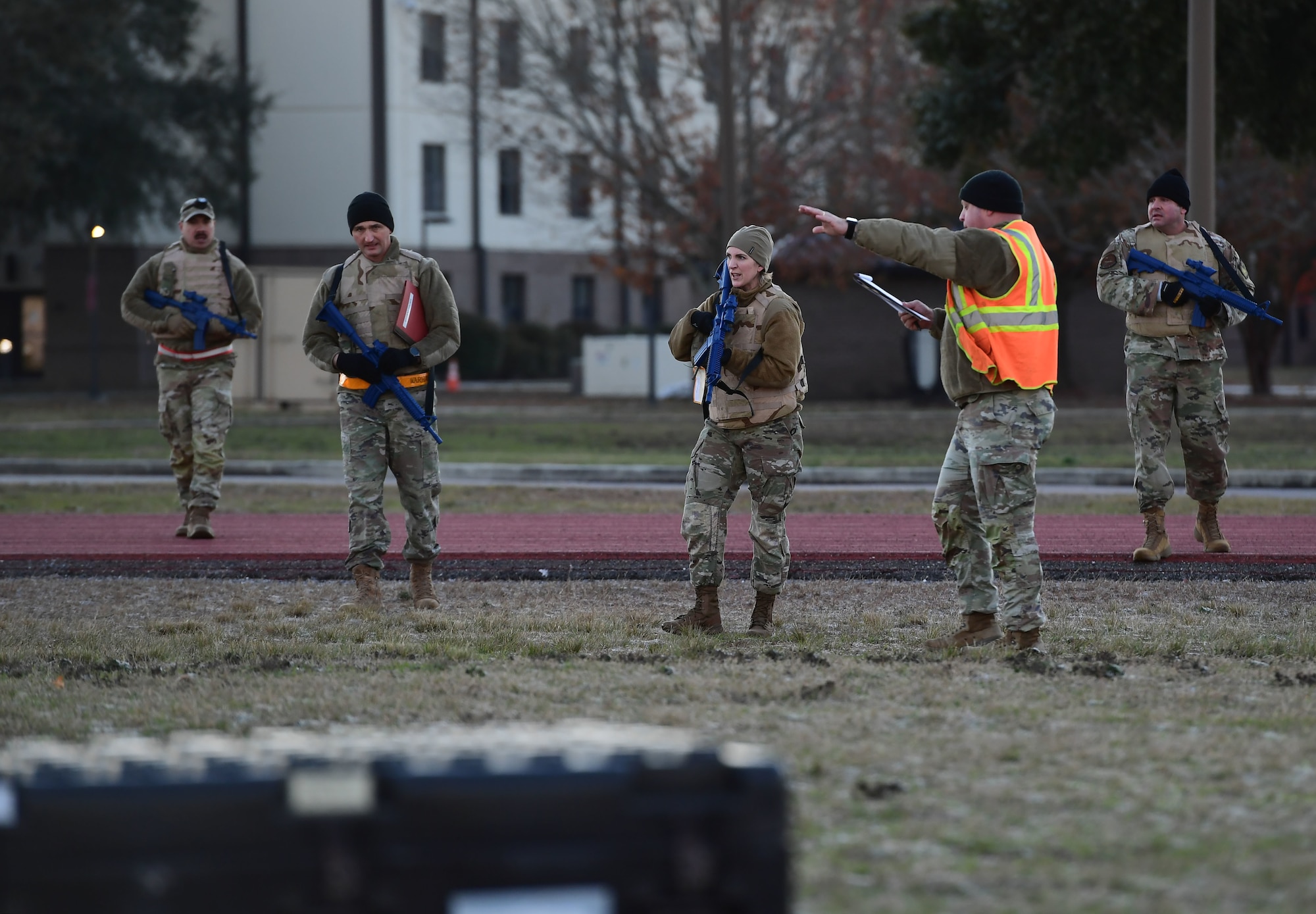 A group of people wearing military uniform hold simulated weapons while standing in a field.