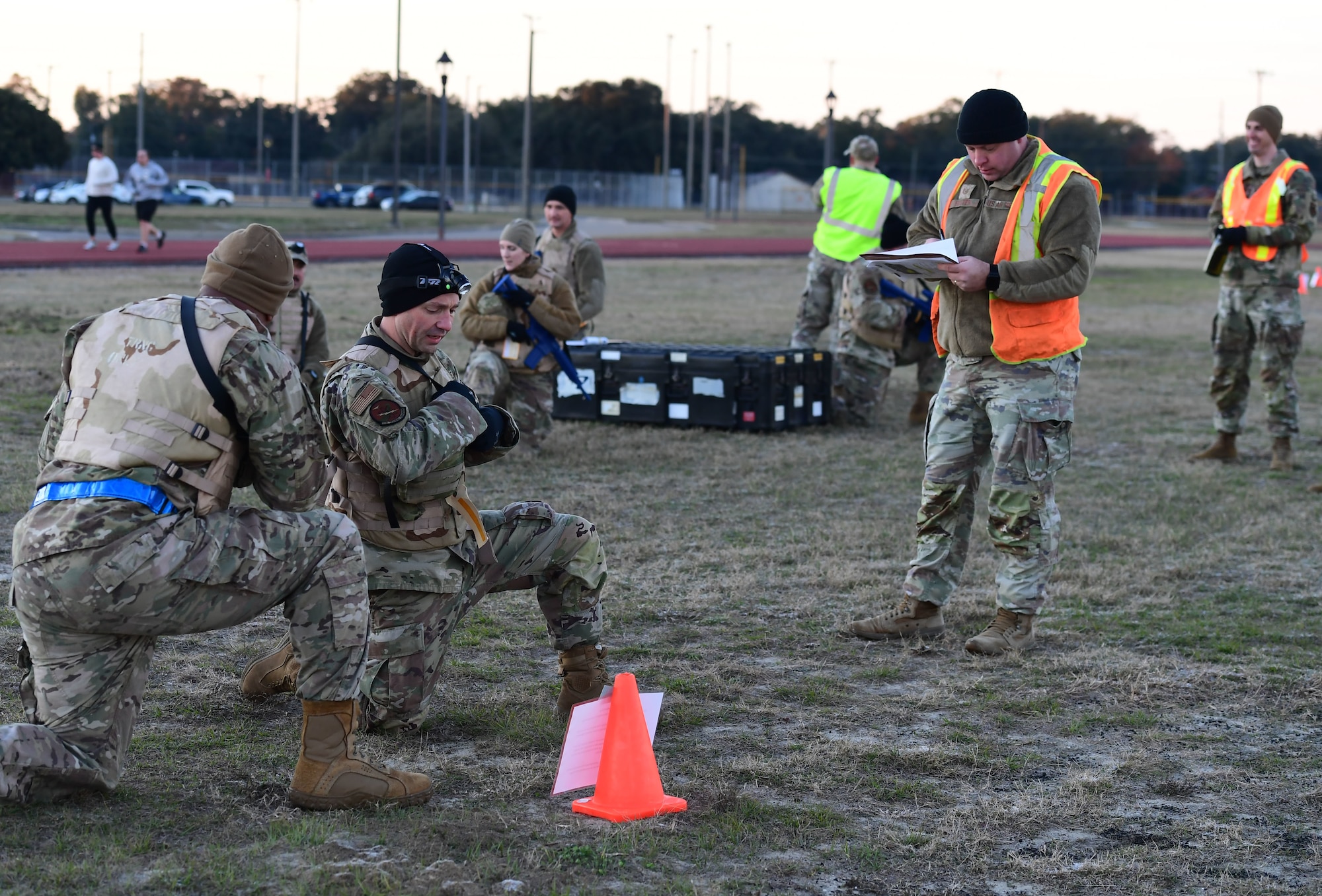 A group of people wearing military uniform are in a field on a knee holding simulated weapons.