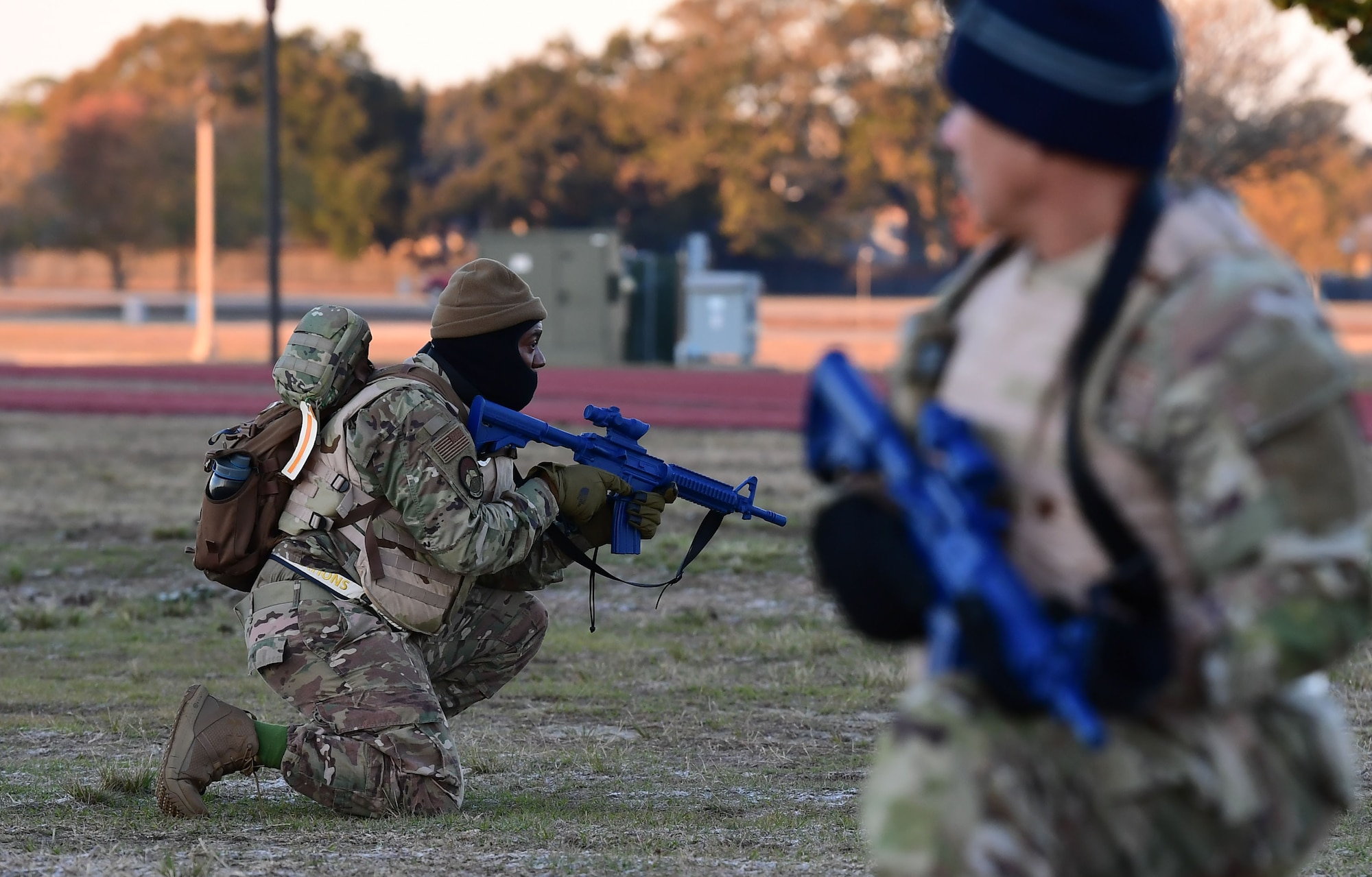 A group of people wearing military uniform carries a large metal box. man in military uniform takes a knee while holding a simulated weapon.