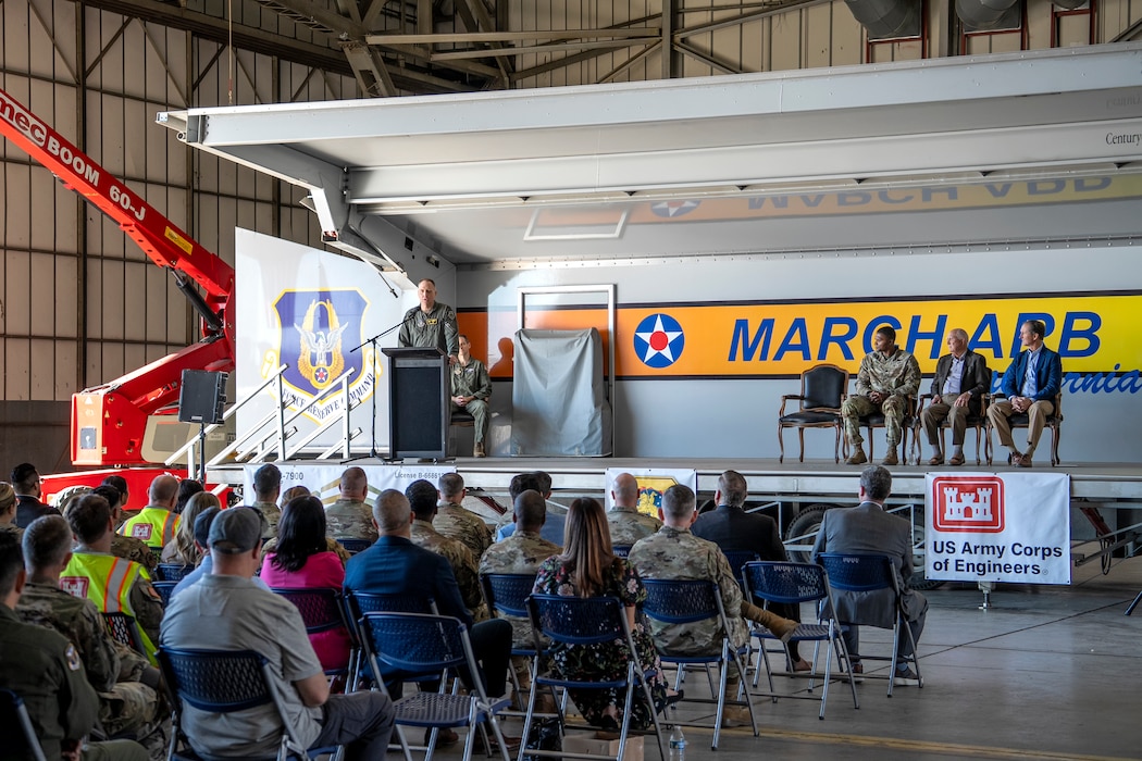 U.S. Air Force Col. Bryan Bailey, commander of the 452nd Air Mobility Wing, on stage at left, addresses attendees during a groundbreaking ceremony for a new KC-46 Pegasus hangar and training facility Dec. 16 at March Air Reserve Base in Riverside County, California.