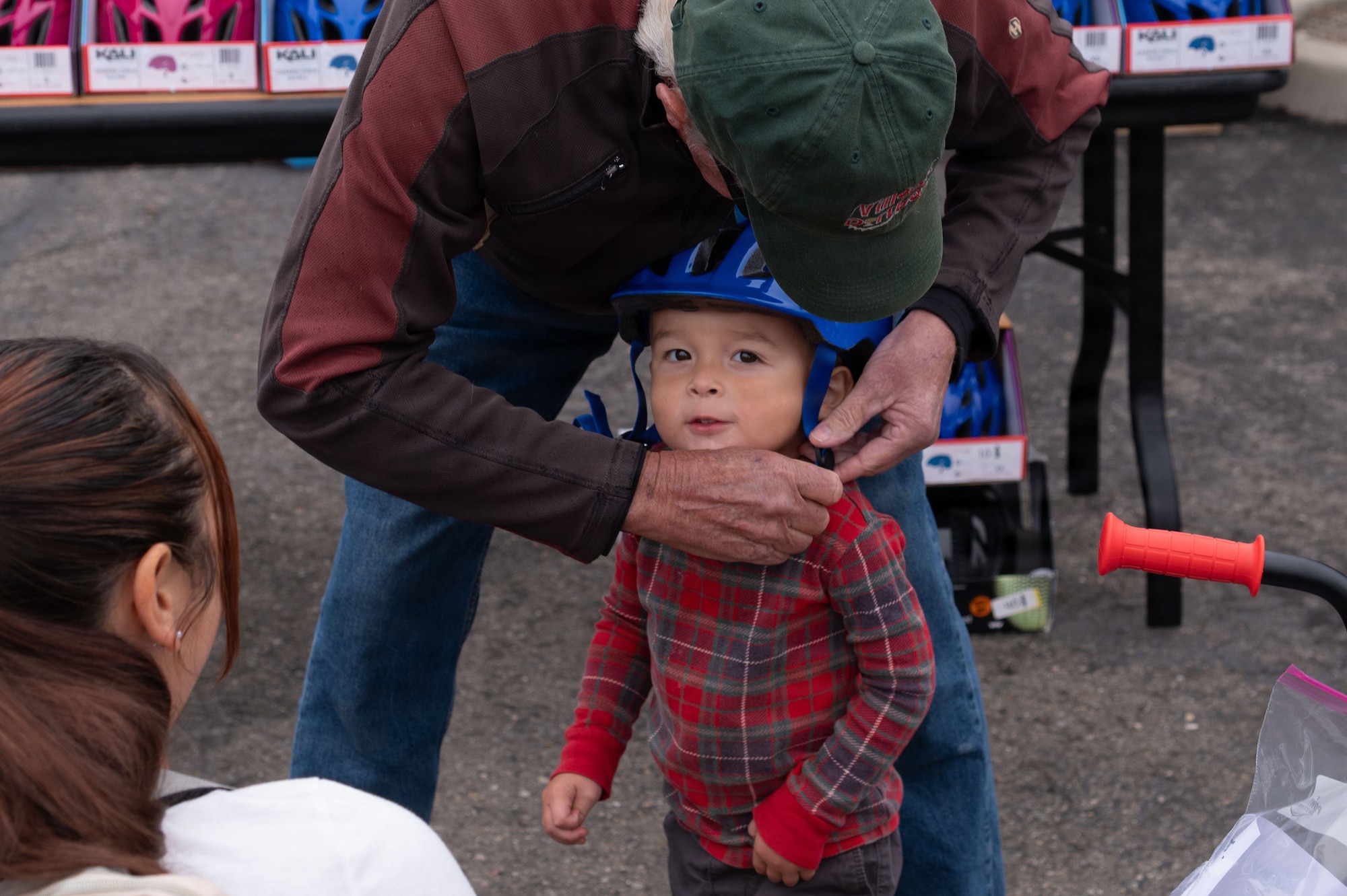 a person straps a helmet onto a young kid