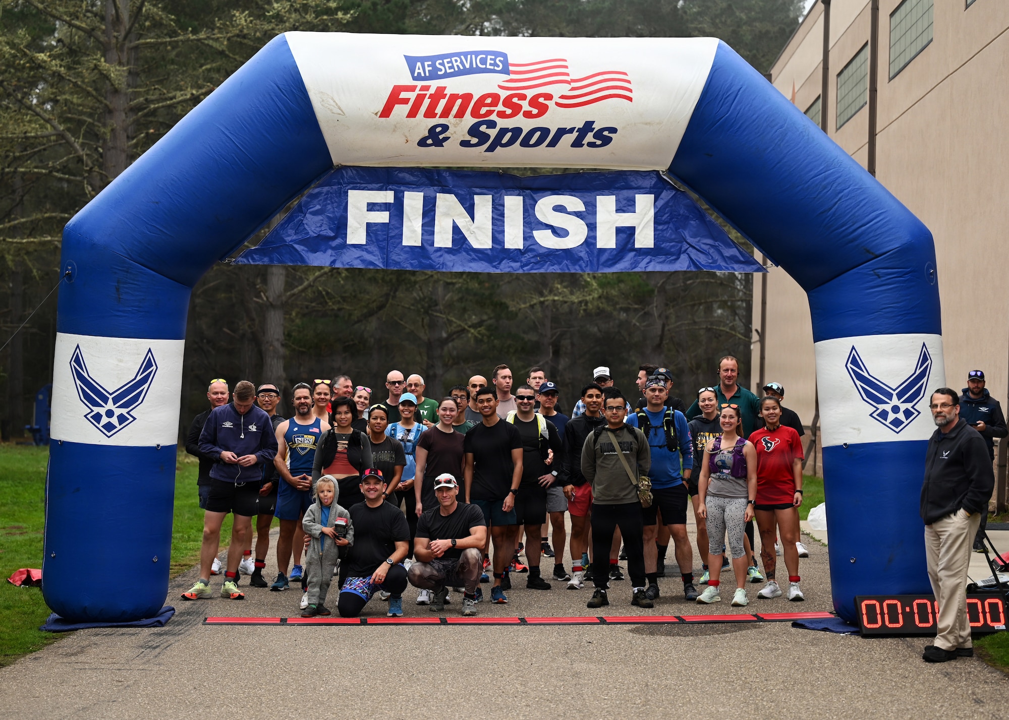 Participants and volunteers pose for a group photo at the finish line following the localized T-Minus 10-Miler at Vandenberg Space Force Base