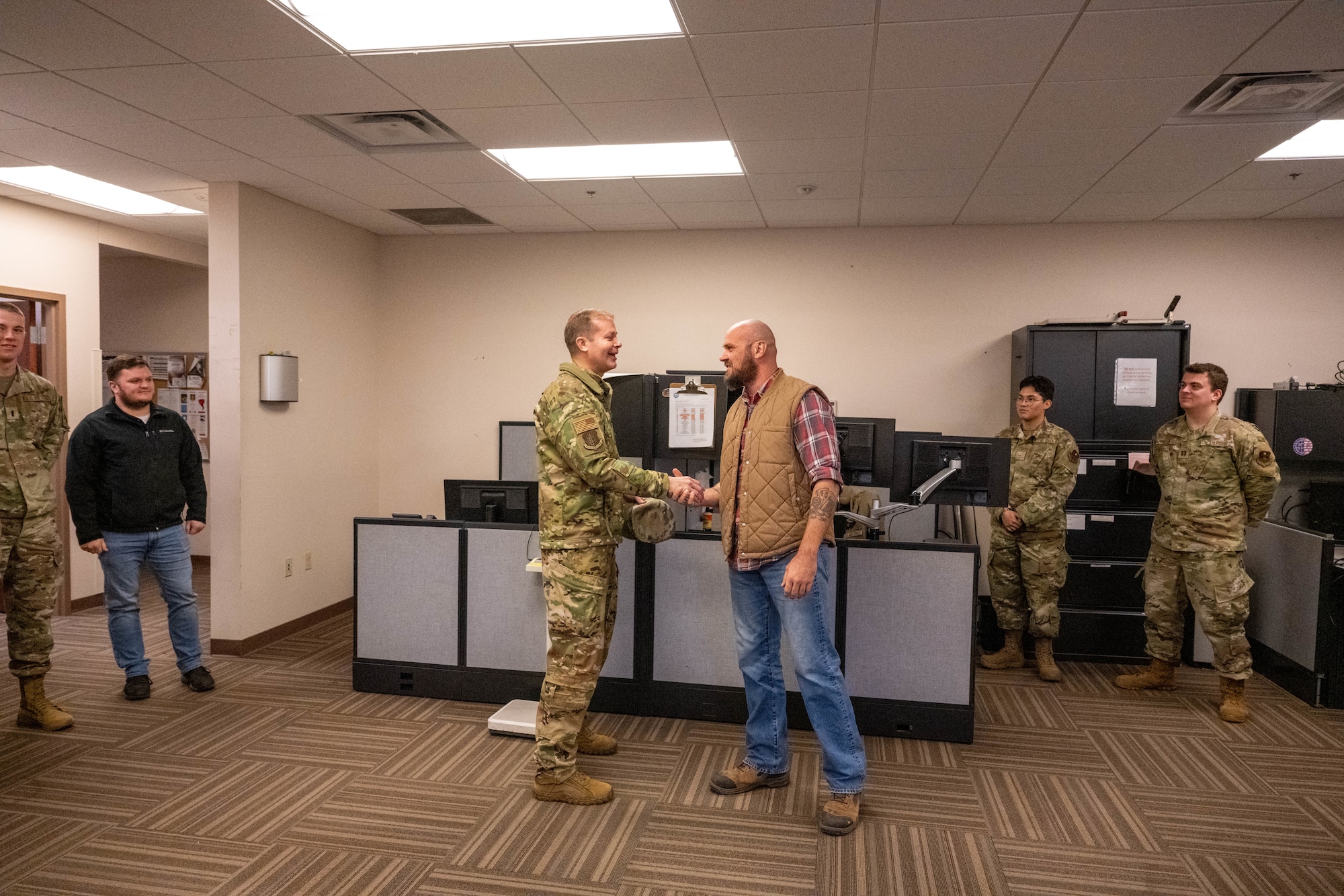 U.S. Air Force Col. Richard Kind, 97th Air Mobility Wing commander, coins Josh Barclay, 97th Operations Support Squadron Radar, Airfield & Weather Systems lead technician, at Altus Air Force Base, Oklahoma, Dec. 15, 2025. Kind presented the 2025 fiscal year Air Education and Training Command (AETC) Airfield Operations Trainer of the Year Award to Barclay to recognize his outstanding performance and reinforce AETC’s commitment to excellence. (U.S. Air Force photo by Airman 1st Class Emma Wright)