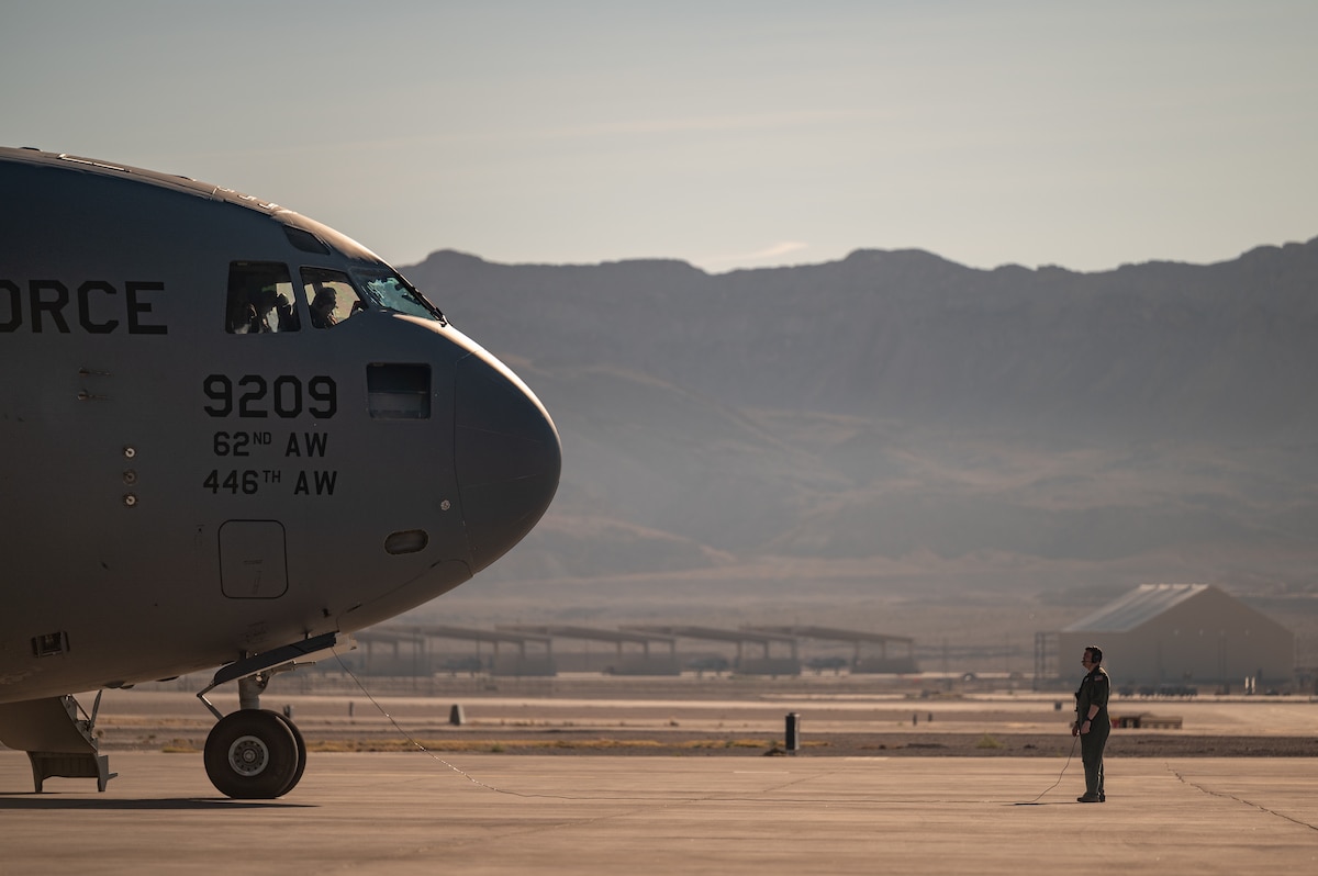 Master Sgt. James Osteen, 57th Weapons Squadron airdrop evaluator loadmaster, U.S. Air Force Weapons School, communicates with pilots of a C-17A Globemaster III before a Weapons School Integration mission at Nellis Air Force Base, Nev., Dec. 9, 2025. The 57th WPS participates in WSINT to conduct complex joint exercises by integrating aircrews with ground forces and combat air components in contested environments. (U.S. Air Force photo by Airman 1st Class Jennifer Nesbitt) 