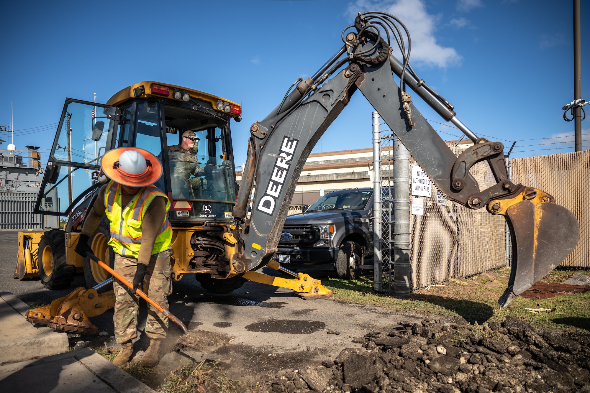 Tech. Sgt. Patrick Lawrence, right, a construction specialist from the Kentucky Air National Guard’s 123rd Civil Engineer Squadron, operates a backhoe to repair pavement at Joint Base Pearl Harbor-Hickam, Hawaii, with help from his active-duty counterparts at the 647th Civil Engineer Squadron on July 29, 2025. Lawrence is among more than 70 Airmen from the Louisville-based 123rd Airlift Wing to conduct annual training here over 14 days, sharpening skills that enhance their global employment as Multi-Capable Airmen. (U.S. Air National Guard photo by Dale Greer)