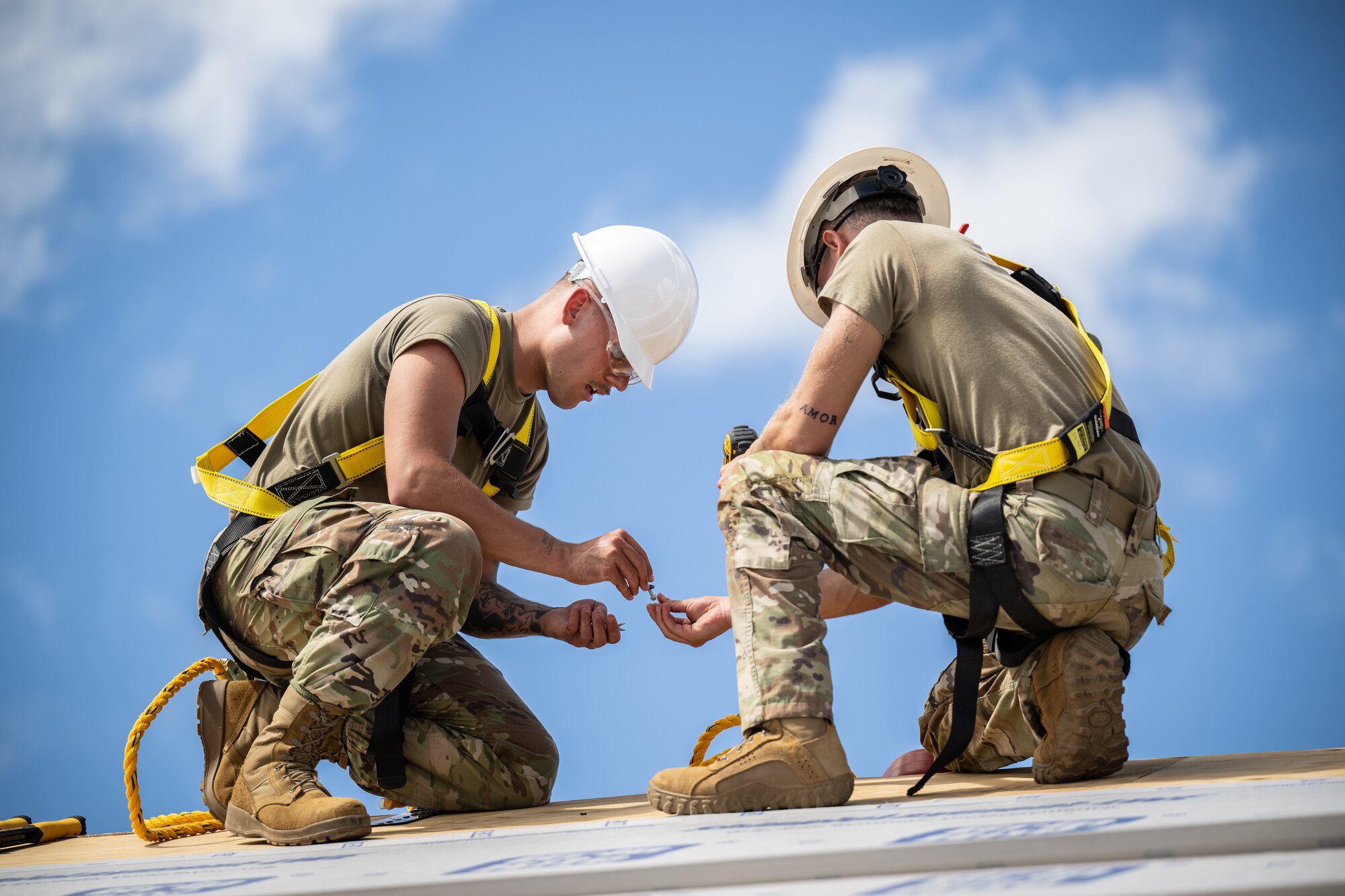 Airman 1st Class Jacob Moore, left, a structures specialist with the Kentucky Air National Guard’s 123rd Civil Engineer Squadron, assists Airman 1st Class Ian Spaulding of the 647th Civil Engineer Squadron to erect an Joint Operations Center on a contingency training site at Joint Base Pearl Harbor-Hickam, Hawaii, on July 29, 2025. Moore is among more than 70 personnel from the Louisville-based 123rd Airlift Wing to conduct annual training here over 14 days, sharpening skills that enhance their employment as Multi-Capable Airmen. (U.S. Air National Guard photo by Dale Greer)