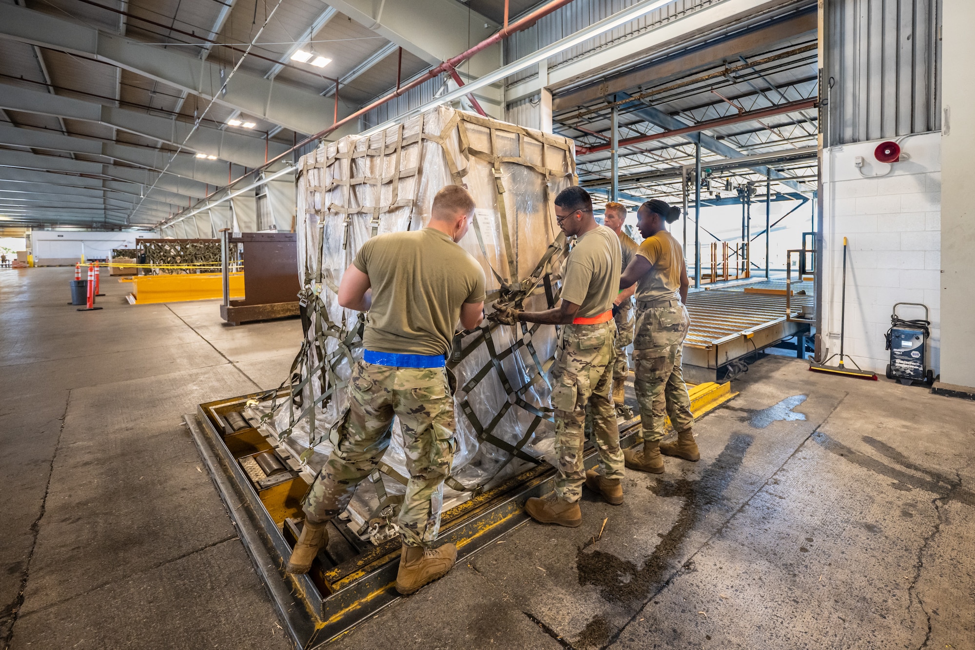 Tech. Sgt. Kevin Kruse, second from right, an aerial porter from the Kentucky Air National Guard’s 123rd Logistics Readiness Squadron, works with active-duty and Air Force Reserve Airmen to tighten the netting on a cargo pallet in a staging warehouse at Joint Base Pearl Harbor-Hickam, Hawaii, on July 30, 2025. Kruse was among more than 70 personnel from the Louisville-based 123rd Airlift Wing to conduct annual training here over 14 days, sharpening skills that enhance their employment as Multi-Capable Airmen. (U.S. Air National Guard photo by Dale Greer)