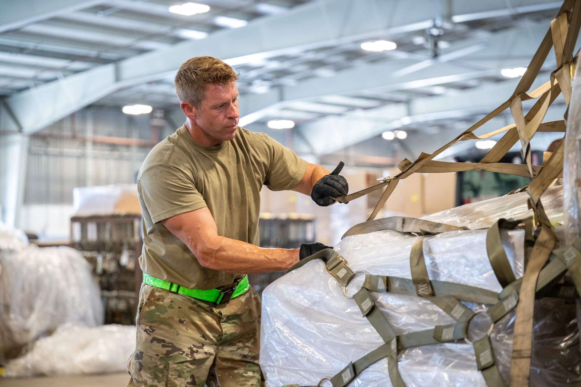 Tech. Sgt. Kevin Kruse, an aerial porter from the Kentucky Air National Guard’s 123rd Logistics Readiness Squadron, tightens netting on a cargo pallet in a staging warehouse at Joint Base Pearl Harbor-Hickam, Hawaii, on July 30, 2025. Kruse was among more than 70 personnel from the Louisville-based 123rd Airlift Wing to conduct annual training here over 14 days, enhancing skills that enhance their employment as Multi-Capable Airmen. (U.S. Air National Guard photo by Dale Greer)