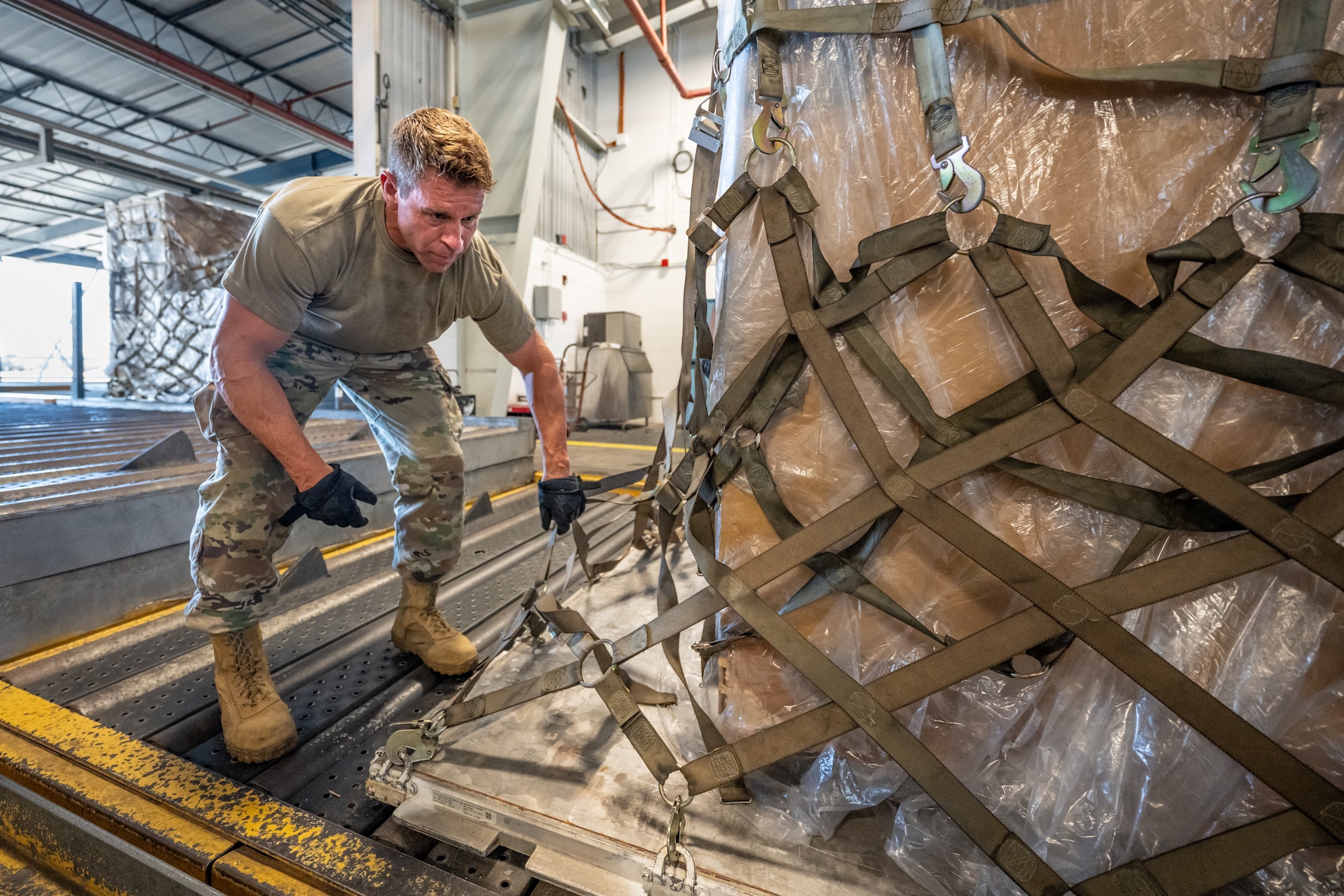 Tech. Sgt. Kevin Kruse, an aerial porter from the Kentucky Air National Guard’s 123rd Logistics Readiness Squadron, tightens netting on a cargo pallet in a staging warehouse at Joint Base Pearl Harbor-Hickam, Hawaii, on July 30, 2025. Kruse was among more than 70 personnel from the Louisville-based 123rd Airlift Wing to conduct annual training here over 14 days, sharpening skills that enhance their employment as Multi-Capable Airmen. (U.S. Air National Guard photo by Dale Greer)