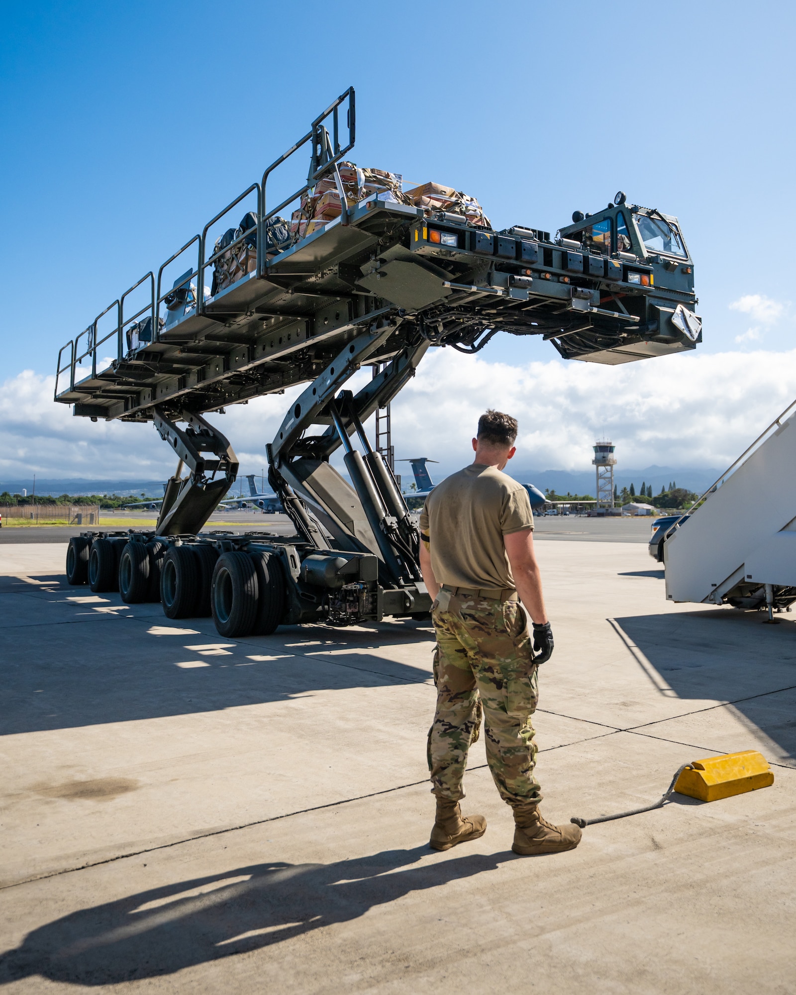 Airman 1st Class Beau Barker, an aerial porter from the Kentucky Air National Guard’s 123rd Logistics Readiness Squadron, prepares to chock the wheels of a Tunner cargo loader on the flight line at Joint Base Pearl Harbor-Hickam, Hawaii, on Aug. 4, 2025. Barker was among more than 70 personnel from the Louisville-based 123rd Airlift Wing to conduct annual training here over 14 days, sharpening skills that enhance their global employment as Multi-Capable Airmen. (U.S. Air National Guard photo by Dale Greer)