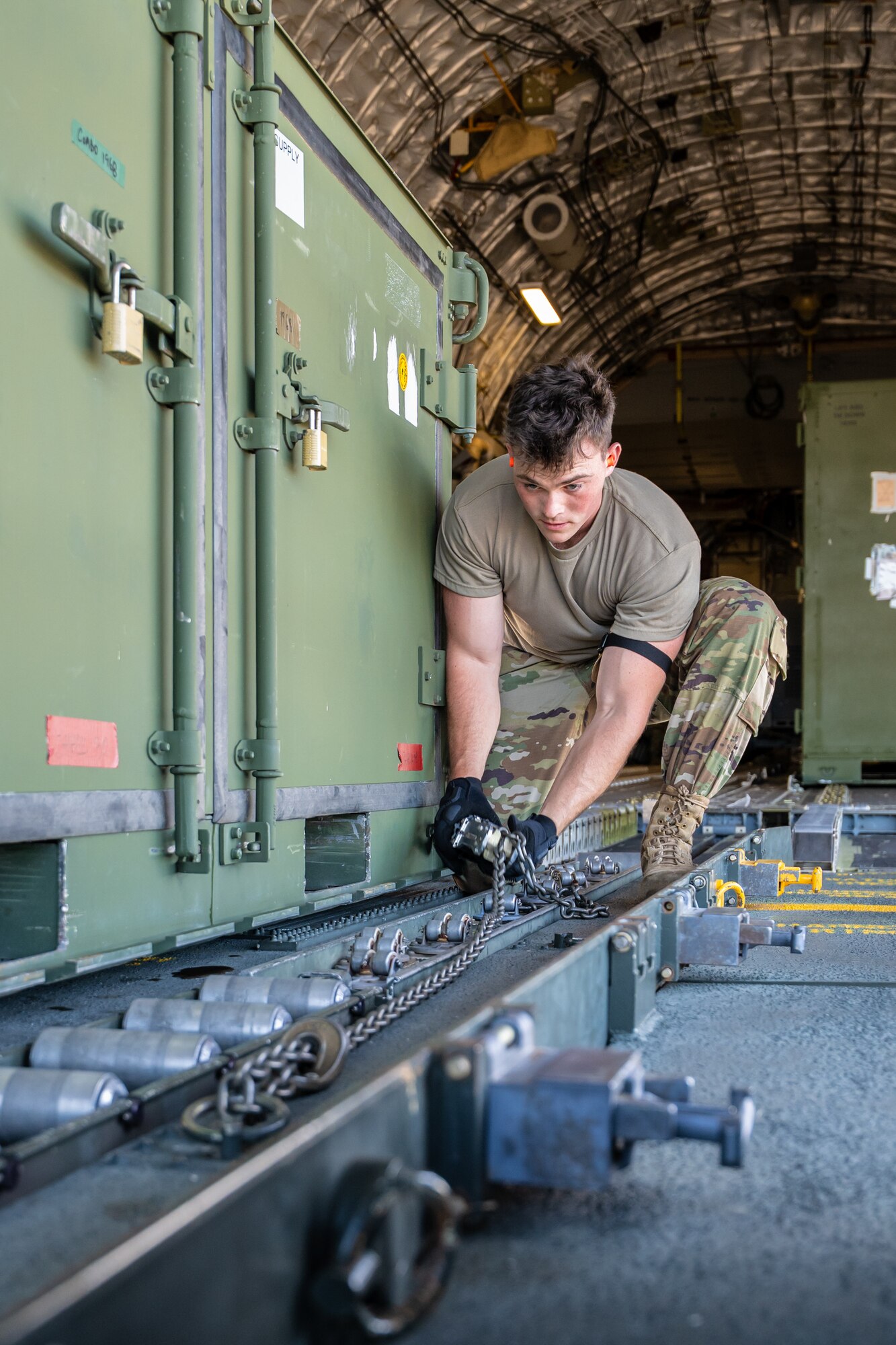 Airman 1st Class Beau Barker, an aerial porter from the Kentucky Air National Guard’s 123rd Logistics Readiness Squadron, tightens chains on a shipping container to secure it to the cargo bay of a U.S. Air Force C-17 Globemaster II aircraft at Joint Base Pearl Harbor-Hickam, Hawaii, on Aug. 5, 2025. Barker was among more than 70 personnel from the Louisville-based 123rd Airlift Wing to conduct annual training here over 14 days, sharpening skills that enhance their global employment as Multi-Capable Airmen. (U.S. Air National Guard photo by Dale Greer)