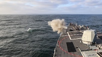 The Arleigh Burke-class guided-missile destroyer, USS Paul Ignatius (DDG 117), fires its Mk 45 5-inch gun during a Naval Surface Firing Support (NSFS) exercise at sea.