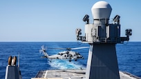A military helicopter lands on the deck of a U.S. Navy command ship