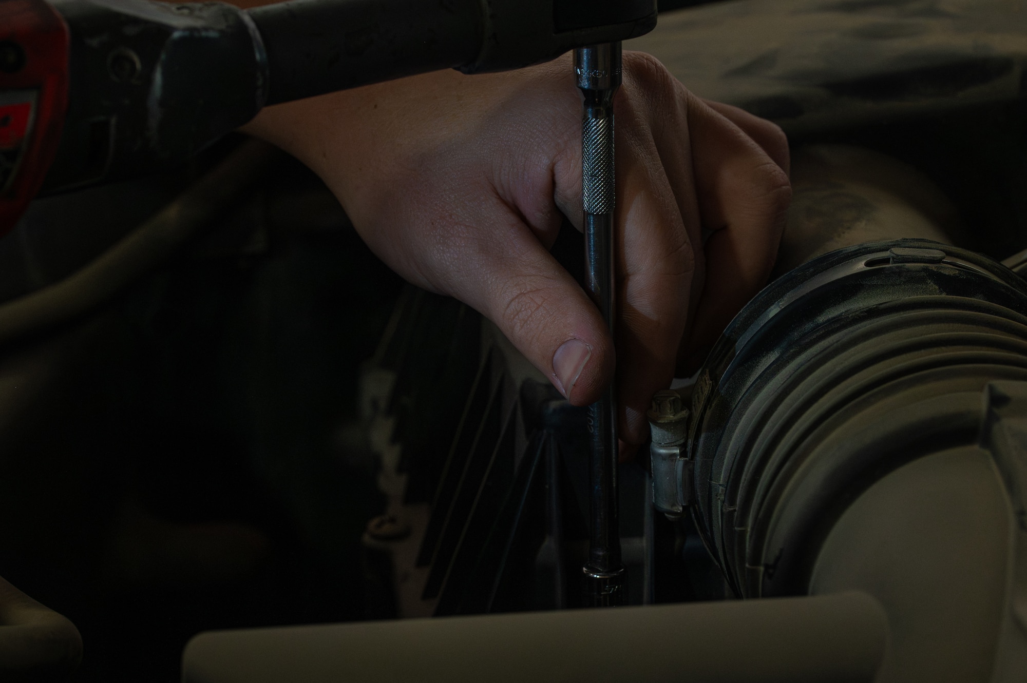 Close up of a hand using a tool on an indiscernible part of a truck