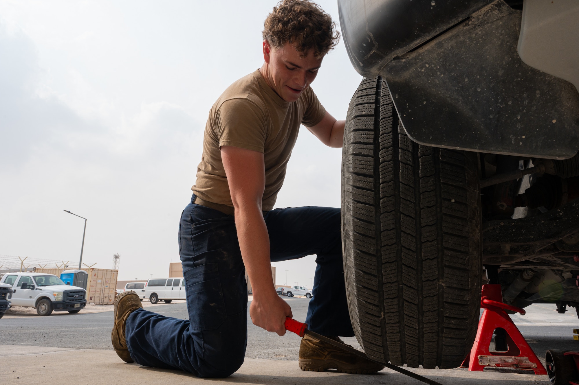 An Airman uses a jack to lift a truck