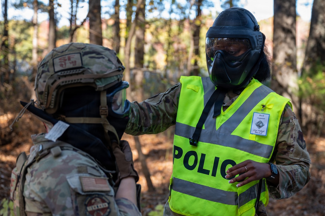 A person in a yellow vest adjusts a facial mask.