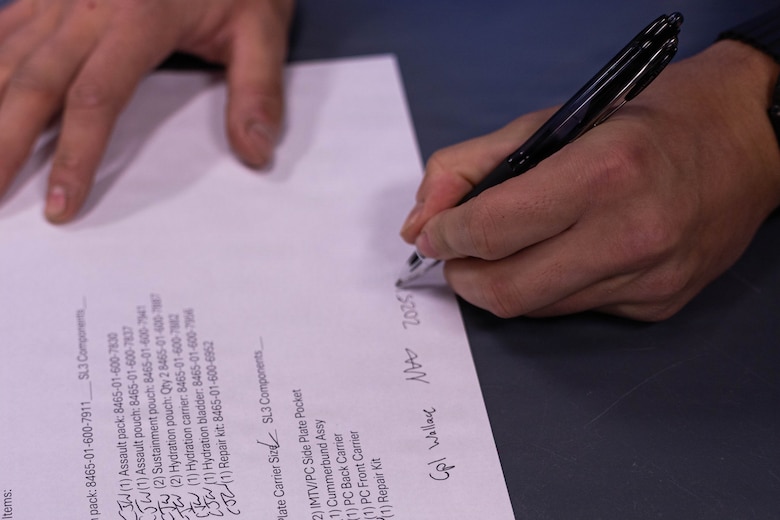 U.S. Marine Corps Cpl. Matthew Wallace signs a Marine’s gear list during a gear issue at Fort Devens, Massachusetts, Dec. 14, 2025. Wallace is a supply administrative clerk with Headquarters and Service Company, 1st Battalion, 25th Marine Regiment. Marines took part in this event as an ongoing effort to prepare and maintain readiness for upcoming training and operations. (U.S. Marine Corps photo by Lance Cpl. Priscilla Flores)