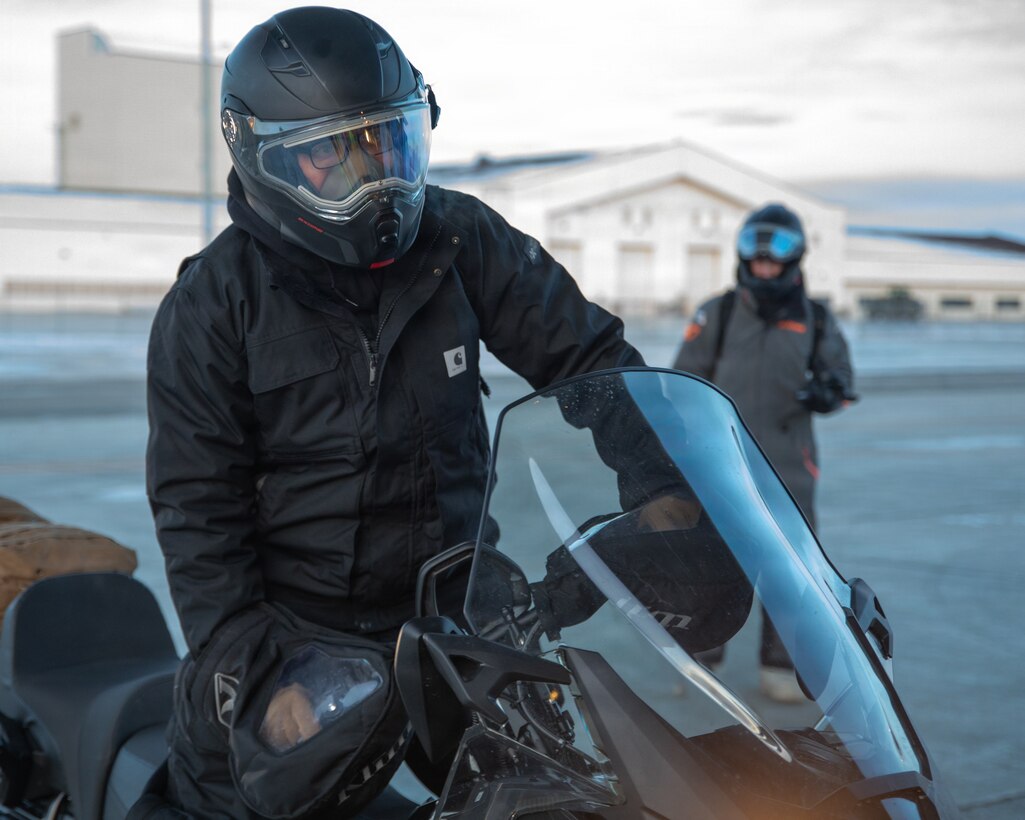 U.S. Marine Corps Cpl. Steven Manning parks a snow machine while Marines off load a KC-130J SUPER HERCULES in Anchorage, Alaska, Dec. 16, 2025. Manning is an administrative clerk with Detachment Delta Company, 4th Law Enforcement Battalion, Force Headquarters Group. The Toys for Tots program highlight the Marine Corps' commitment to community support in the Arctic, while also enhancing the Marines’ preparedness for cold-weather operations. (U.S. Marine Corps photo by Cpl. Orion Stpierre)