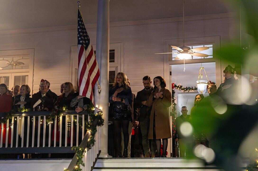 Military veterans, local officials and civilians affiliated with the military community stand as the Marine Forces Reserve band plays The Star-Spangled Banner during the annual Christmas party held at Quarters A in New Orleans, Dec. 6, 2025. The event supported the Marine Corps Reserve Toys for Tots program, with guests contributing donations throughout the evening, and featured a concert by the Marine Forces Reserve Band as its main attraction. (U.S. Marine Corps photo by Lance Cpl. Priscilla Flores)