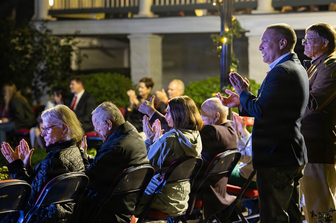Military veterans, local officials and civilians affiliated with the military community applaud a live performance during the annual Christmas party held at Quarters A in New Orleans, Dec. 6, 2025. The event supported the Marine Corps Reserve Toys for Tots program, with guests contributing donations throughout the evening, and featured a concert by the Marine Forces Reserve Band as its main attraction. (U.S. Marine Corps photo by Lance Cpl. Priscilla Flores)