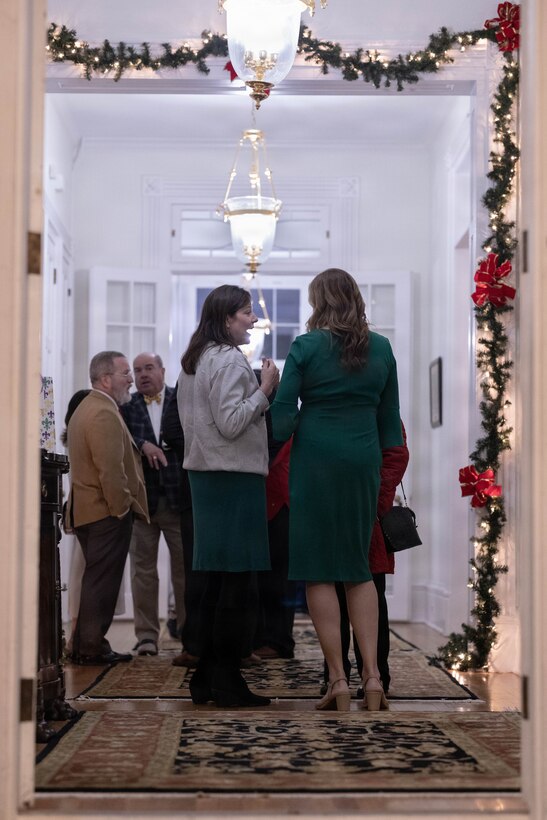 Military veterans, local officials and civilians affiliated with the military community conversate in the hallway during the annual Christmas party held at Quarters A in New Orleans, Dec. 6, 2025. The event supported the Marine Corps Reserve Toys for Tots program, with guests contributing donations throughout the evening, and featured a concert by the Marine Forces Reserve Band as its main attraction. (U.S. Marine Corps photo by Lance Cpl. Priscilla Flores)