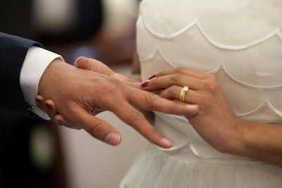 Woman in a wedding dress puts a ring on a man's hand