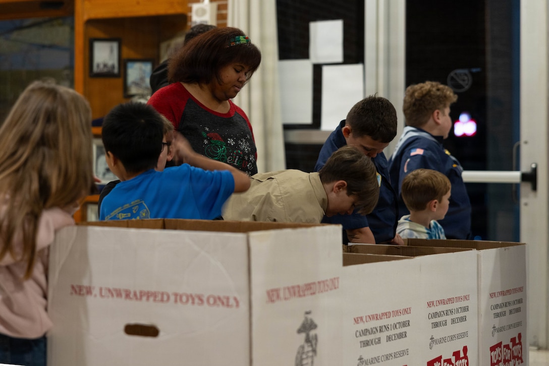 Community members and children collect toys at the Morgan City Municipal Auditorium, Morgan City, Louisiana, Dec. 9, 2025. The Marine Forces Reserve Band performed for the local community to listen to holiday music in the areas surrounding New Orleans while supporting the collecting of new, unwrapped toys for Toys for Tots. (U.S. Marine Corps photo by Lance Cpl. Priscilla Flores)