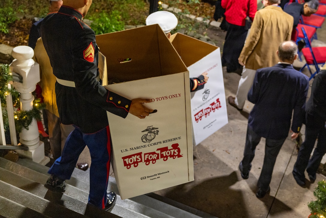 Toys for Tots collection boxes are carried down the stairs during the Christmas party hosted by Lt. Gen Leonard F. Anderson IV, commander of Marine Forces Reserve and Marine Forces South, at Quarters A in New Orleans, Dec. 6, 2025. The event supported the Marine Corps Reserve Toys for Tots program, with attendees contributing donations throughout the evening. (U.S. Marine Corps photo by Sgt. Samuel Qin)