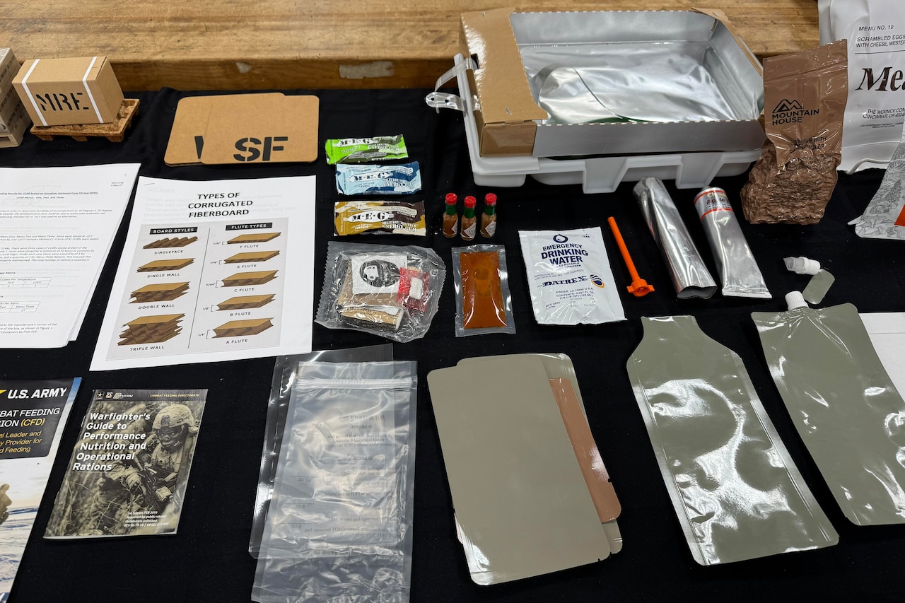 A table is covered in plastic pouches, some that are filled and some that aren’t. There are also brochures and other items.