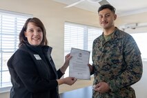 Lauren Bolen, interim director of the American Red Cross, left, presents Cpl. Malikah Warren, 2nd Distribution Support Battalion, 2nd Marine Logistics Group, right, with the Red Cross Lifesaving Award on Marine Corps Base Camp Lejeune, North Carolina, Dec. 16, 2025. The Marines received the Lifesaving Award, the second highest award the American Red Cross bestows, for rescuing people during an emergency at a local beach earlier this year. (U.S. Marine Corps photo by Lance Cpl. Erica S. Padgett)