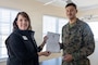 Lauren Bolen, interim director of the American Red Cross, left, presents Cpl. Malikah Warren, 2nd Distribution Support Battalion, 2nd Marine Logistics Group, right, with the Red Cross Lifesaving Award on Marine Corps Base Camp Lejeune, North Carolina, Dec. 16, 2025. The Marines received the Lifesaving Award, the second highest award the American Red Cross bestows, for rescuing people during an emergency at a local beach earlier this year. (U.S. Marine Corps photo by Lance Cpl. Erica S. Padgett)