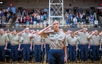 group photo of older teens in khaki shirts and navy pants saluting indoors