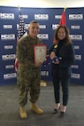 U.S. Marine Corps Brig. Gen. Ralph J. Rizzo, Jr., commanding general, Marine Corps Installations East – Marine Corps Base (MCIEAST-MCB) Camp Lejeune presents a folded National Ensign to Sarah Wiltgen at her retirement ceremony at MCCS headquarters on MCB Camp Lejeune, Dec. 12, 2025. During her 11-year tenure as assistant chief of staff for Marine Corps Community Services, MCIEAST, Wiltgen's steadfast leadership was pivotal in navigating MCCS’s support of MCIEAST installations through major challenges to include Hurricane Florence and the COVID-19 pandemic. She was a dedicated advocate for Marines, sailors, and their families, championing several highly-successful pilot programs that directly enhanced their well-being.