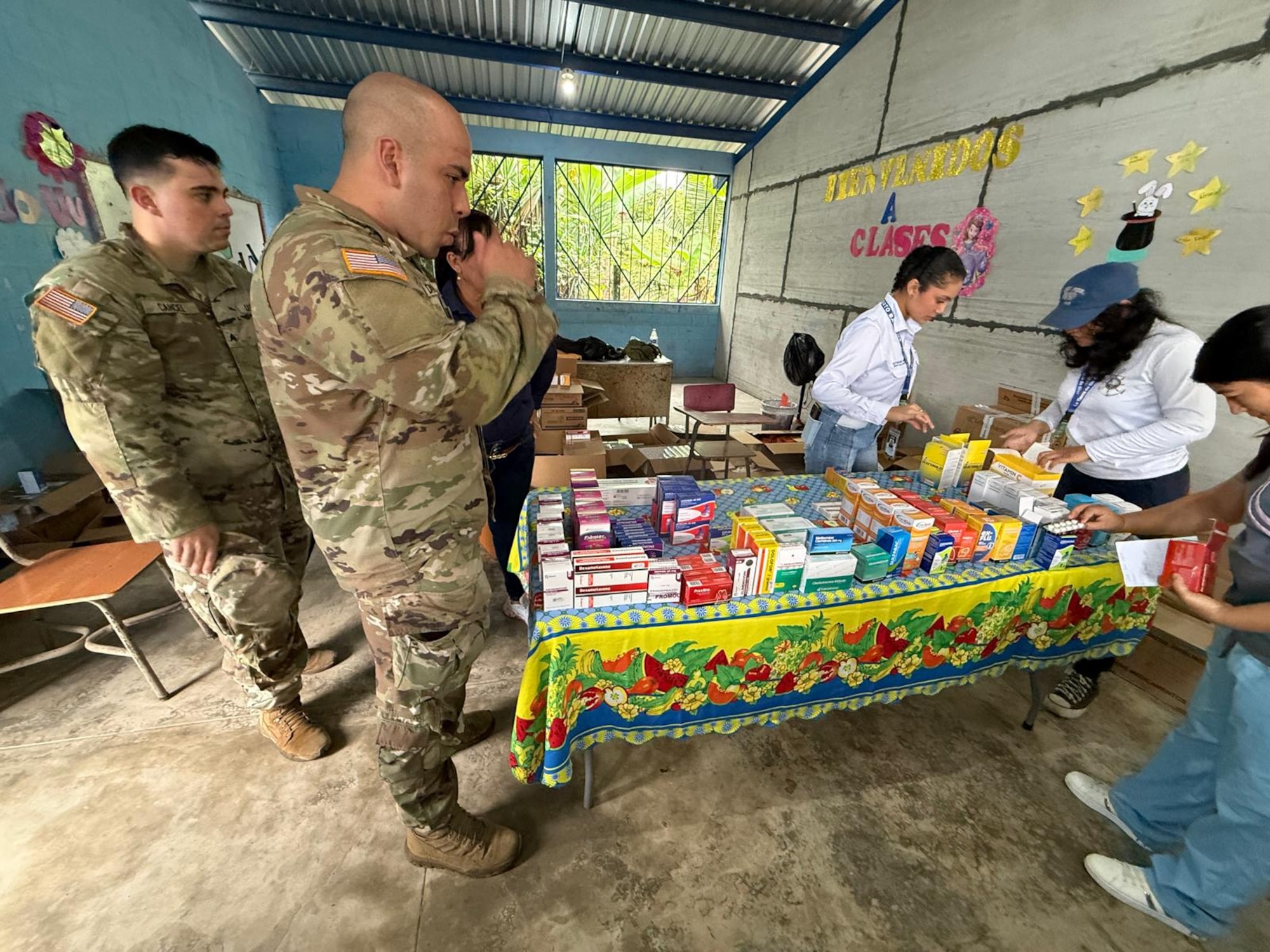 People in military uniforms and civilian clothing sort medical supplies.