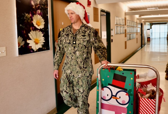 TWENTYNINE PALMS, Calif. (Dec. 17, 2025) — Chaplain Lt. Cmdr. Nicholas Suddath wheels a cart of donated toys to place beneath the hospital’s Angel Tree at Naval Hospital Twentynine Palms. The Angel Tree program provides holiday gifts to children of active-duty Sailors through anonymous community donations. (U.S. Navy photo by Christopher Jones/NMRTC Twentynine Palms Public Affairs Officer)