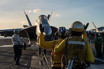 U.S. Navy Sailors direct an F/A-18F Super Hornet, attached to Strike Fighter Squadron (VFA) 41, on the flight deck of Nimitz-class aircraft carrier USS Abraham Lincoln (CVN 72) in the Philippine Sea, Dec. 19, 2025. The Abraham Lincoln Carrier Strike Group is underway conducting routine operations in the U.S. 7th Fleet area of operations. Units assigned to U.S. 7th Fleet conduct regular Indo-Pacific patrols to deter aggression, strengthen alliances and partnerships, and advance peace through strength. (U.S. Navy photo by Mass Communication Specialist 3rd Class Nathaly Cruz)