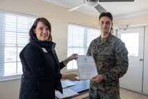 Lauren Bolen, interim director of the American Red Cross, presents Cpl. Zbigniew Adamczyk, Marine Medium Tiltrotor Training Squadron 204, Marine Aircraft Group 26, 2nd Marine Aircraft Wing, with the Red Cross Lifesaving Award on Marine Corps Base Camp Lejeune, North Carolina, Dec. 16, 2025. The Marines received the Lifesaving Award, the second highest award the American Red Cross bestows, for rescuing people during an emergency at a local beach earlier this year. (U.S. Marine Corps photo by Lance Cpl. Erica S. Padgett)