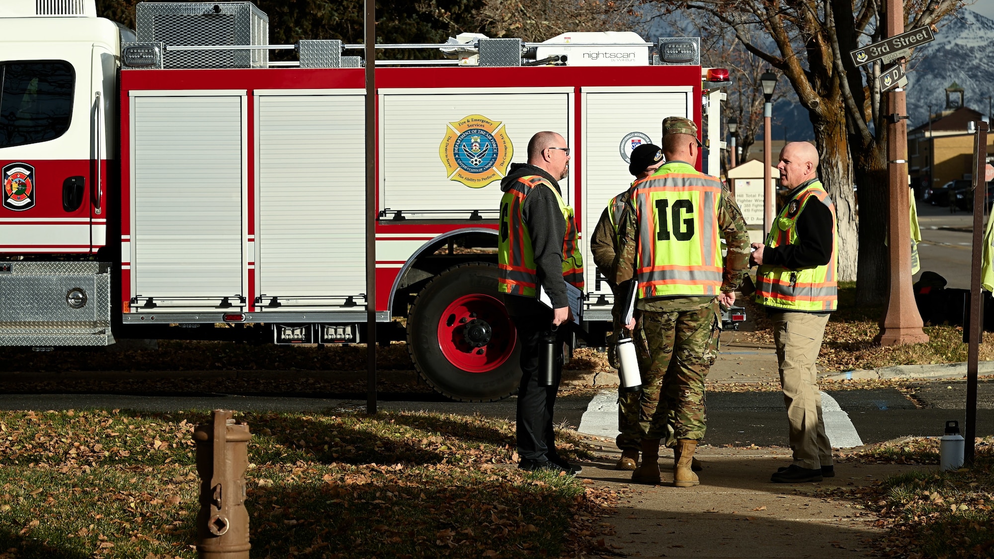 Four Wing Inspection Team members stand in a circle in front of a fire truck talking to each other.