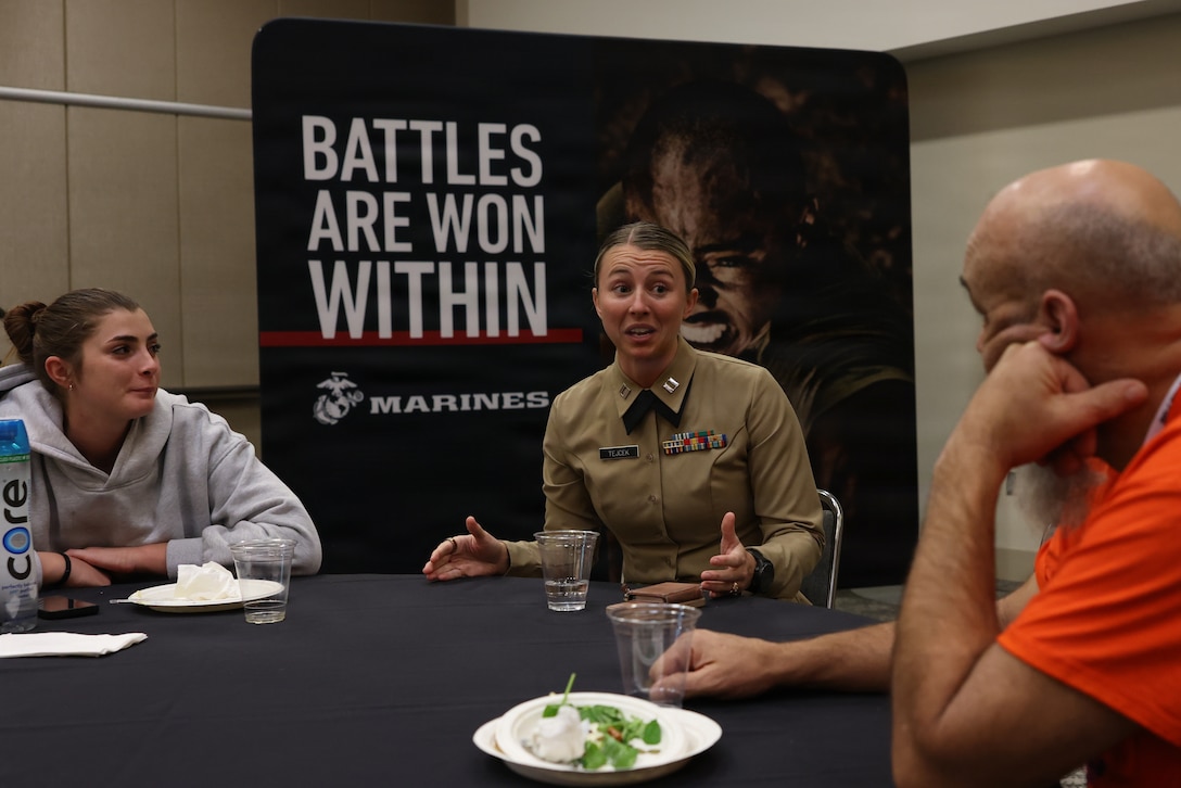 U.S. Marine Corps Capt. Riley Tejcek, an officer procurement officer with the Western Recruiting Region, center, engages with coaches during the Fit to Win Coaches Luncheon and Workshop at the 2025 American Volleyball Coaches Association convention in Kansas City, Missouri, Dec. 18, 2025. The Fit to Win session offered coaches an immersive introduction to Marine Corps training principles and provided coaches with practical tools they can carry back to their programs. (U.S. Marine Corps photo by Cpl. Hana Lathrop)
