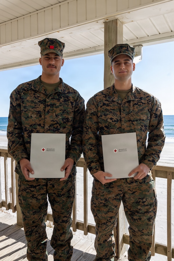 U.S. Marine Corps Cpl. Malikah Warren, 2nd Distribution Support Battalion, 2nd Marine Logistics Group, left, and Cpl. Zbigniew Adamczyk, Marine Medium Tiltrotor Training Squadron 204, Marine Aircraft Group 26, 2nd Marine Aircraft Wing, right, pose for a photo after receiving Red Cross Lifesaving Awards on Marine Corps Base Camp Lejeune, North Carolina, Dec. 16, 2025. The Marines received the Lifesaving Award, the second highest award the American Red Cross bestows, for rescuing people during an emergency at a local beach earlier this year. (U.S. Marine Corps photo by Lance Cpl. Erica S. Padgett)