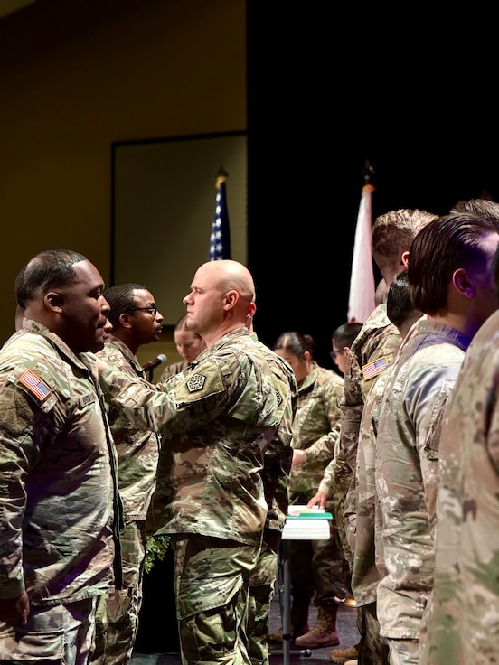 Maj. (promotable) Benjamin Reeder, Commander of the 198th Combat Sustainment Support Battalion, pins military medals on 725th Transportation Company Soldiers during the unit’s Welcome Home Ceremony.