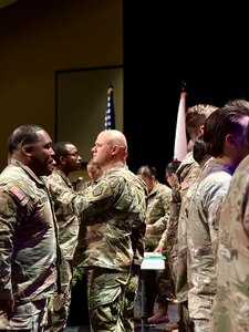 Maj. (promotable) Benjamin Reeder, Commander of the 198th Combat Sustainment Support Battalion, pins military medals on 725th Transportation Company Soldiers during the unit’s Welcome Home Ceremony.